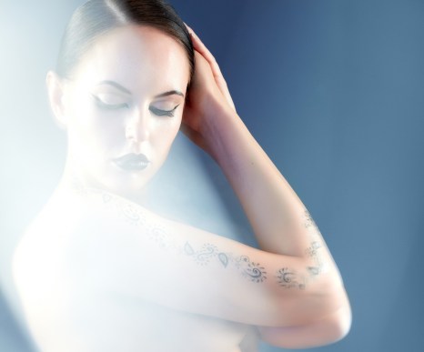 Portrait of naked woman with tattoo surrounded by mist